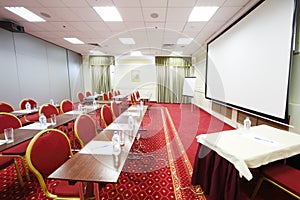 Tables with bottles, red chairs and projector in