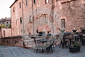 Tables and chairs of a bar in an alley of a medieval village Gubbio, Italy