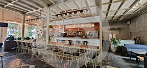 Tables and chairs for dining in a restaurant with an industrial design style with bare concrete floors with natural accents.