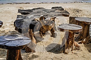 tables and chairs made of tree trunks with a sea background.