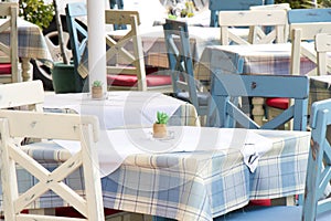 Tables and chairs in a typical traditional  Medierranean restaurant on terrace in light blue and white color photo