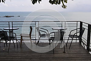 Tables and chairs on wooden floor in a cafe by the sea background