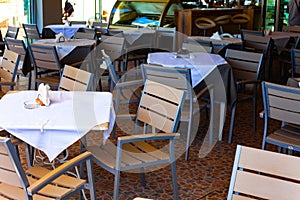 Tables in the restaurant with white table cloth and white napkins in the holder.