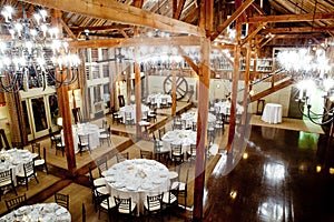 Tables set inside a big dark barn during a wedding reception