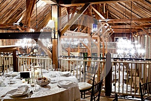 Tables set inside a dark barn during a wedding reception