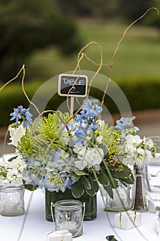 Tables set for an outdoor wedding reception in white, with blue flowers as decor