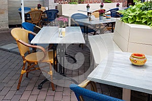 Tables and wooden chairs in a open air restaurant.