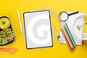 Tablet with blank screen, school supplies and lunch box