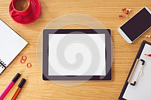 Tablet with blank white screen on wooden table. Office desk mock up. View from above