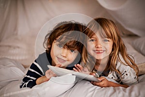 Tablet, blanket fort and portrait of kids relaxing, bonding and playing together at home. Happy, smile and young girl