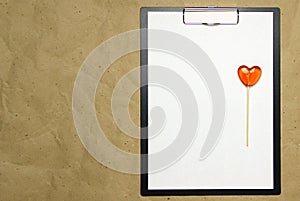 The tablet with a clip for the clip of paper with a white sheet a4 lies against the background of craft brown crumpled