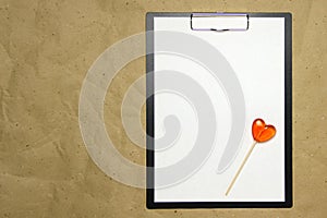 The tablet with a clip for the clip of paper with a white sheet a4 lies against the background of craft brown crumpled