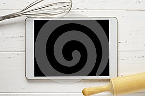 A tablet computer and cooking battery on a white background. Copy space. Concept of cooking recipes