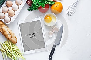 Tablet computer with fresh vegetables on white background, copy space