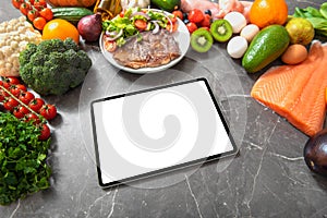 Tablet computer on a kitchen table surrounded by healthy products