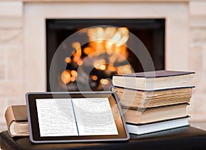 Tablet computer and pile books on the background of the fireplace