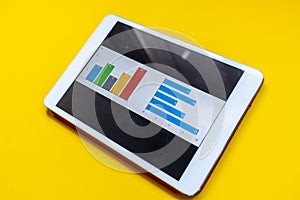 Tablet with diagram and report on a yellow background. Office environment. Business concept