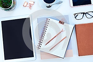 Tablet, diary and coffee on desk in studio for working, writing notes and planning for career. Creative workplace