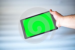 Tablet with green screen fastened with one hand on white background