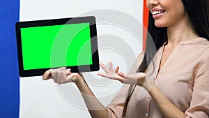 Tablet with green screen in female hands, France flag background, traveling app