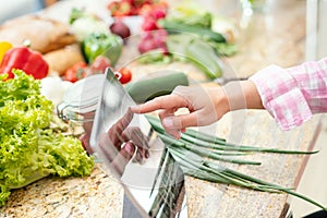 Tablet and a hand of a woman looking for recipes