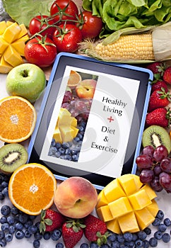 Un tablet computer, circondata da frutta fresca e verdura.