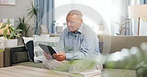Tablet, home and senior man on sofa, reading email or ebook in living room to relax. Retirement, technology and elderly