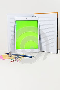 Tablet leaned on the open notebook on the table