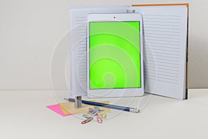 Tablet leaned on the open notebook on the table