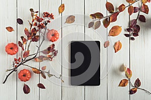 Tablet with leaves, small pumpkins and rowan on white retro wood boards. background. Autumn, fall concept. Flat lay, top view.
