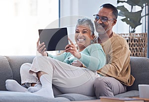 Tablet, love and relax with a senior couple sitting on a sofa in the living room of their home together. Funny, joke and