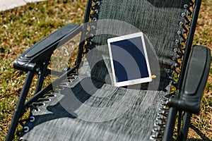 A tablet lying on an empty black hammock chair