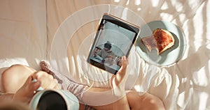 Tablet, movie or girl hand with coffee on bed for breakfast in morning, streaming video or social network app top view