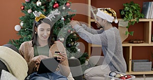 Tablet, online shopping and couple at Christmas in home with discount on gift and holiday decoration. People, celebrate