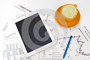 Tablet pc, cup of coffee and paper with graphs