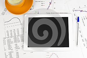 Tablet pc, cup of coffee and paper with graphs