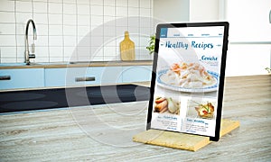 tablet pc with healthy recipes blog screen on cooking island at