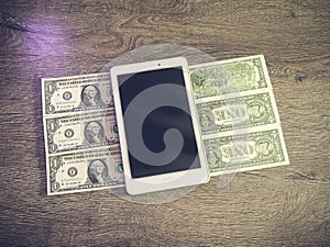 Tablet pc lying on dollars