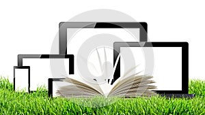 Tablet pc, mobile phone, computer and open book in green grass