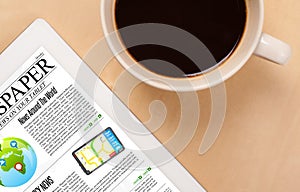 Tablet pc shows news on screen with a cup of coffee on a desk