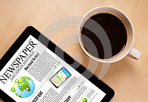 Tablet pc shows news on screen with a cup of coffee on a desk