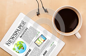 Tablet pc shows news on screen with a cup of coffee on a desk