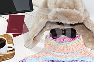 A tablet personal computer with a bright color sweater and warm hat. It is time to leave.