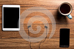 Tablet and phone with coffee on wood with headphones