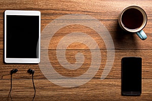 Tablet and phone with coffee on wood with headphones