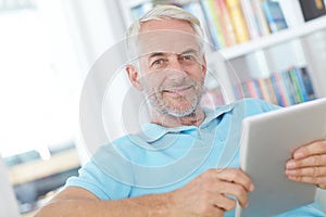 Tablet, portrait or relax senior man doing internet, web or online website search while happy in home living room