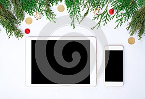 Tablet smart phone display on table on white screen for mockup in Christmas time. Christmas tree, decorations
