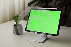 Tablet on stand with green background. Minimalism interior with homeplants