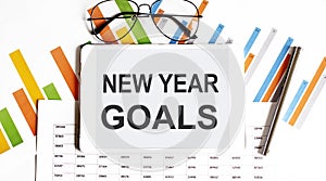 The tablet with text NEW YEAR GOALS on the business charts and pen