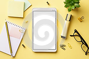 A tablet with white blank screen on an office desk. Flat lay